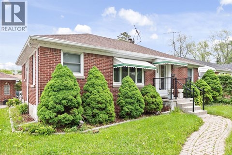 A red brick house with a green lawn in front.