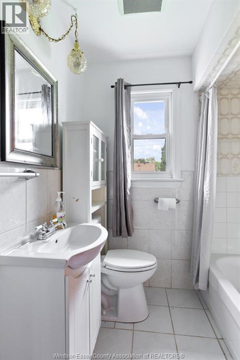 A white bathroom with a toilet, sink, and shower.