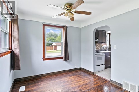 A room with a ceiling fan and a window overlooking a backyard.