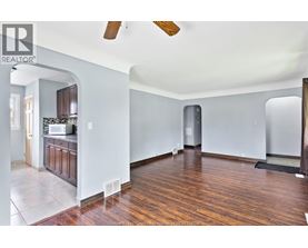 A large empty room with wooden floors and a ceiling fan.