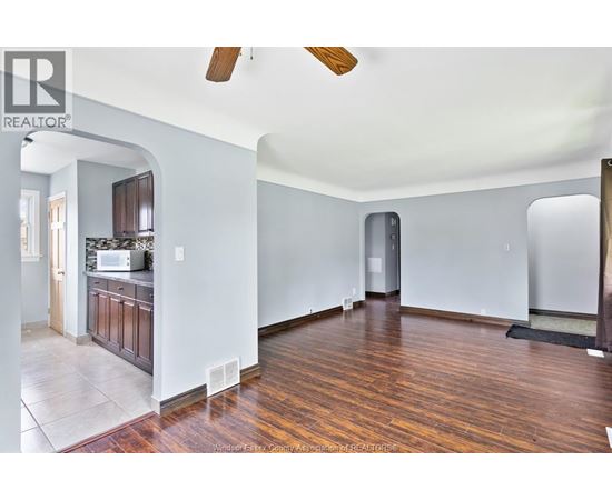 A large empty room with wooden floors and a ceiling fan.