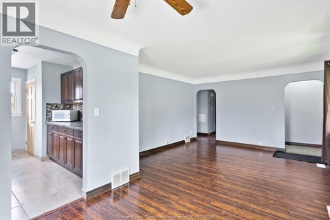 A large empty room with wooden floors and a ceiling fan.