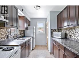 A kitchen with dark wood cabinets and a white stove top oven.