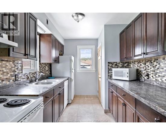 A kitchen with dark wood cabinets and a white stove top oven.