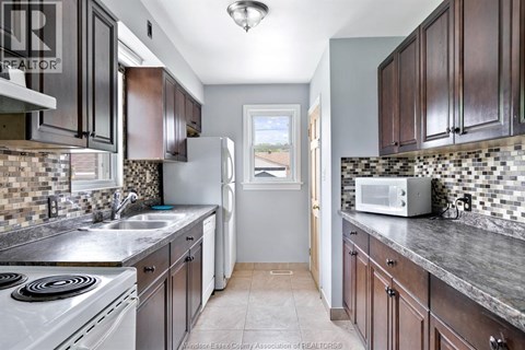 A kitchen with dark wood cabinets and a white stove top oven.