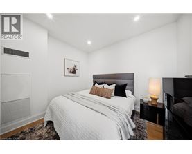 A bedroom with a large bed and a nightstand with a lamp.