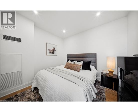 A bedroom with a large bed and a nightstand with a lamp.