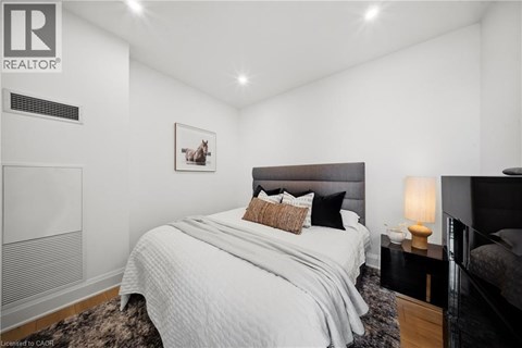 A bedroom with a large bed and a nightstand with a lamp.