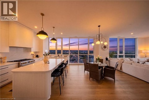 A well-lit, modern kitchen and dining area with a view of the cityscape at dusk.