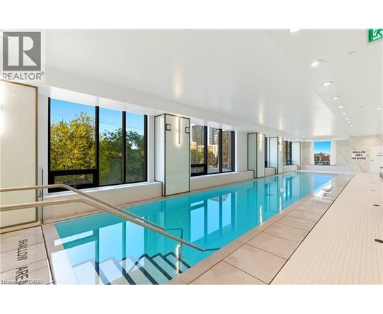 A swimming pool inside a building with a glass wall.