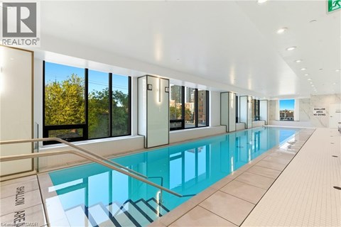 A swimming pool inside a building with a glass wall.