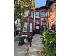 A red brick house with a black door and steps leading up to it.