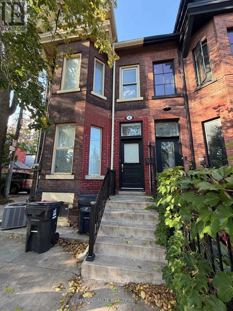 A red brick house with a black door and steps leading up to it.