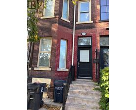 A red brick building with a black door and steps leading up to it.
