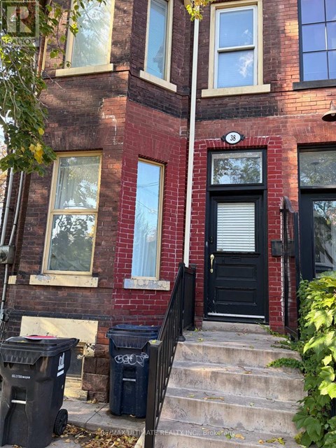 A red brick building with a black door and steps leading up to it.