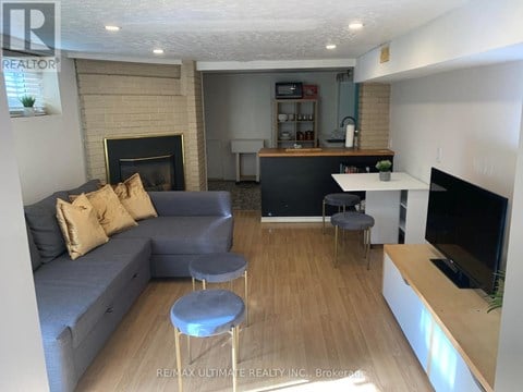 A living room with a grey couch and a fireplace.