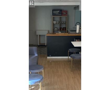A kitchen with a black counter and grey chairs.