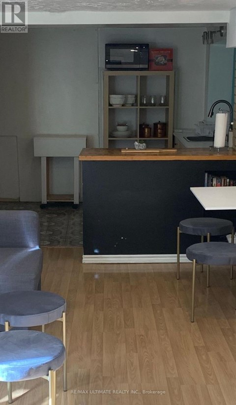 A kitchen with a black counter and grey chairs.
