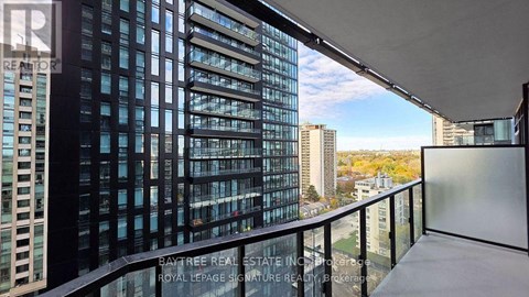 A balcony with a view of a cityscape and a building with the words "Bay Tree Real Estate" on it.