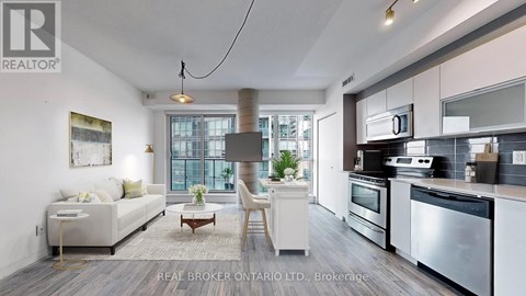 A modern kitchen with stainless steel appliances and a dining area with a white sofa and chairs.