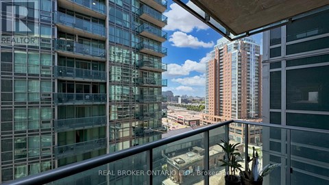 A balcony overlooks a cityscape with buildings and a clear sky.