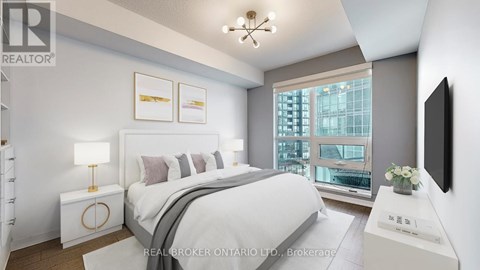 A bedroom with a large bed, a lamp, and a window overlooking a cityscape.