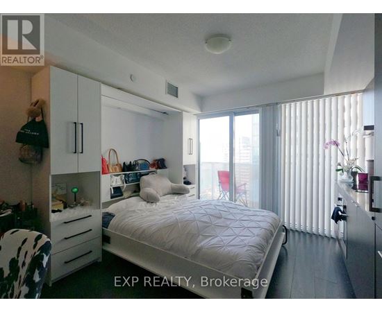 A bedroom with a bed, a chair, and a wardrobe.