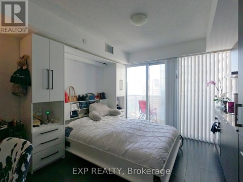 A bedroom with a bed, a chair, and a wardrobe.