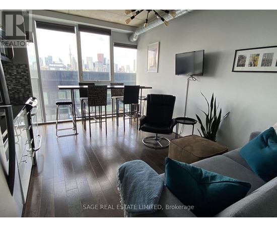 A living room with a grey couch and a television on the wall.