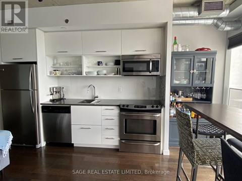 A kitchen with a refrigerator, oven, and sink.