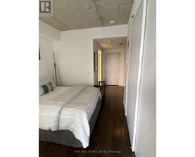 A bedroom with a bed and a doorway leading to another room.