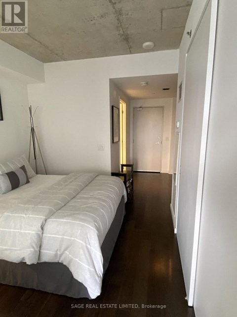 A bedroom with a bed and a doorway leading to another room.