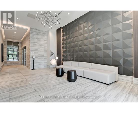 A modern living room with a white sofa and a geometric wall design.