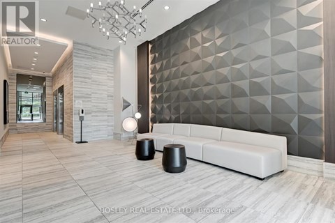 A modern living room with a white sofa and a geometric wall design.