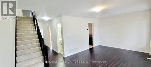 A spacious room with a staircase and a door leading to another room.