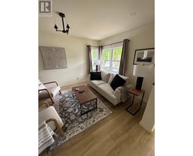 A living room with a white couch, a wooden coffee table, and a rug.
