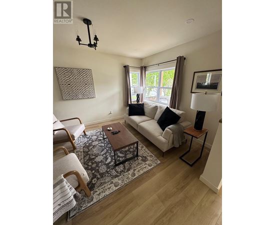 A living room with a white couch, a wooden coffee table, and a rug.