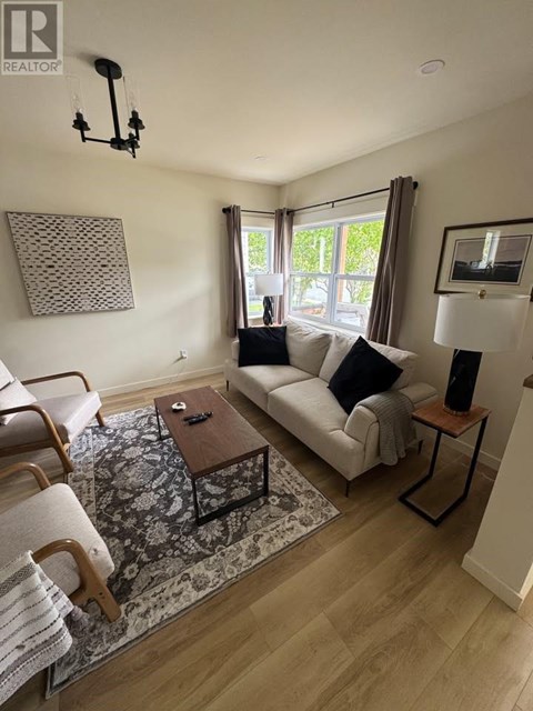 A living room with a white couch, a wooden coffee table, and a rug.