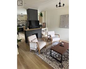 A living room with a fireplace and two chairs.
