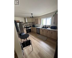 A kitchen with wooden floors and a black chair.