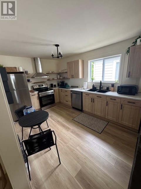 A kitchen with wooden floors and a black chair.