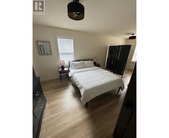 A bedroom with a large bed and a wooden floor.