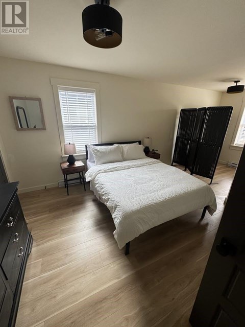 A bedroom with a large bed and a wooden floor.