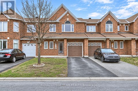 A large brick house with a tree in front and two cars parked in the driveway.