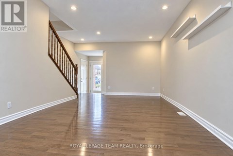 A spacious room with wooden flooring and a staircase.