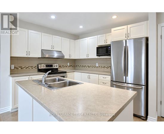 A kitchen with white cabinets and a stainless steel refrigerator.