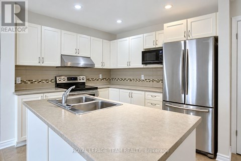 A kitchen with white cabinets and a stainless steel refrigerator.