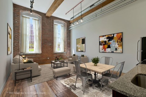 A living room with a brick wall and a dining table.