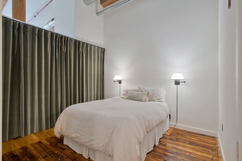 A bedroom with a bed, two lamps, and a curtain.