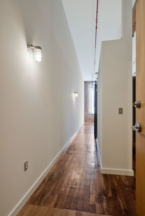 A hallway with a wooden floor and white walls.